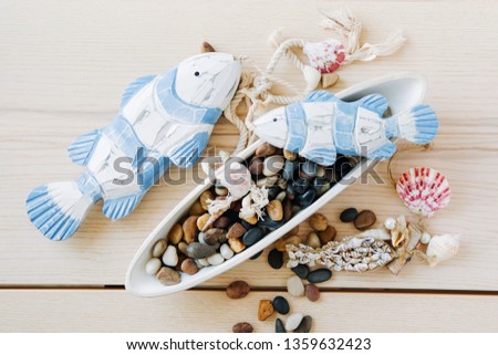Decorative fish with sea pebbles  on a  wooden background. Nautical concept.