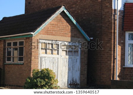 An old 1930's brick suburban garage in England. An old garage built in the 1930's with wooden door in the suburbs of an English city.
