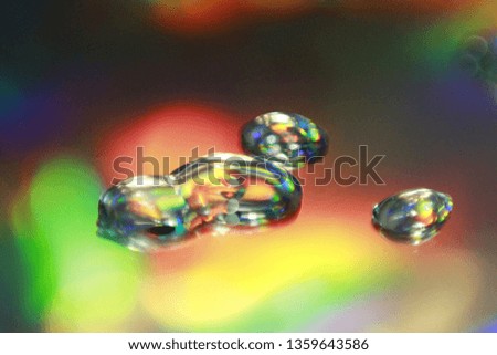 Water drops with glitter and shimmer on mirror cause light interference and refraction effect, color diffraction. Iridescent blurred holographic surface with liquid fluid stains.