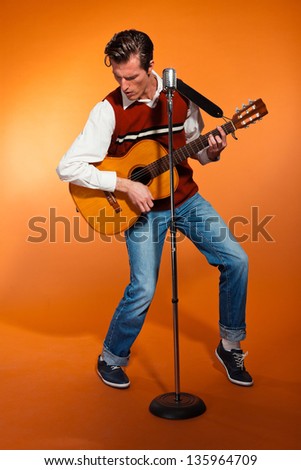 Retro fifties rock and roll singer playing acoustic guitar. Studio shot.