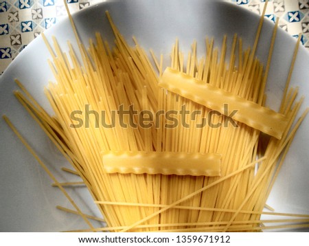 RAW PASTA ON A WHITE DISH ILLUMINATED BY THE SUN THROUGH THE WINDOW CURTAINS WITH SHADOWS