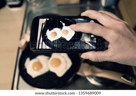 Take a picture of cooking eggs with smart phone.Sending photo message to social media.Photography of egg breakfast on phone camera. 