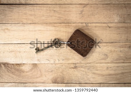 Vintage house key with wooden home keyring on old wood background, copy space