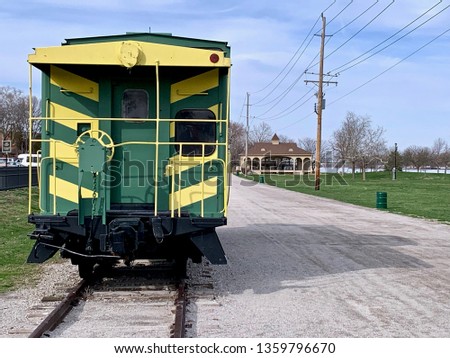 A train caboose sitting by itself on railroad tracks. Royalty-Free Stock Photo #1359796670