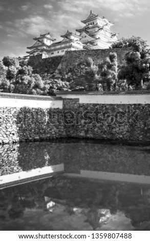 View of Himeji Castle in black and white against the sky and reflected in Mikuni pond, located in Kansai area, Hyogo Prefecture, Japan. It is the most beautiful example medieval Japanese architecture.
