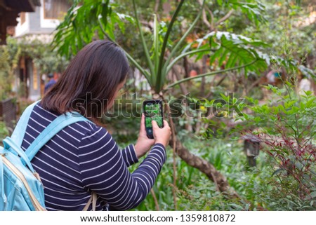 Young Chinese lady taking a photo using Smart phone at Kunming, China
