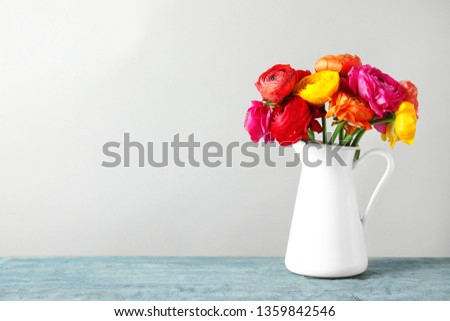 Vase with beautiful spring ranunculus flowers on table, space for text
