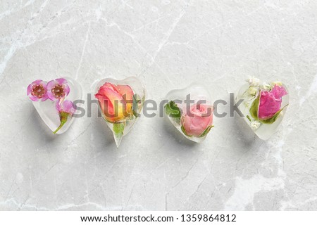Heart shaped floral ice cubes on light background, top view