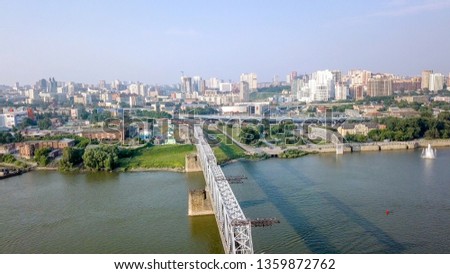 The electric train crosses the Ob river. First Railway Bridge in Novosibirsk. Panorama of the city of Novosibirsk. Russia, From Dron  