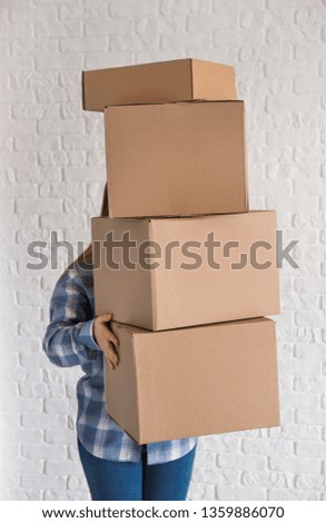 Woman with moving boxes near brick wall