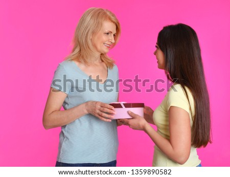 Young woman congratulating her mature mom on color background. Happy Mother's Day