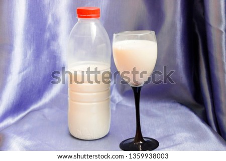 pictured in the photo Bottle and glass of milk on blue background.
