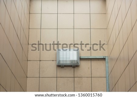 The building of the shopping center is faced with beige ceramic tiles. Electric flap closed lid. The texture of the walls with tiles.