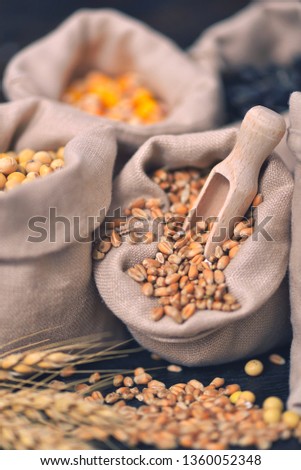 Small bags with various grains and cereals on wooden table, top view, copy space