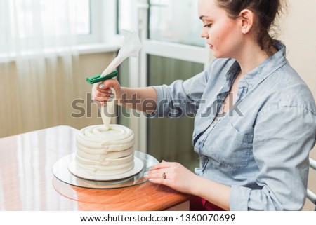 confectioner squeezes the cream on the cake. Girl making a cake