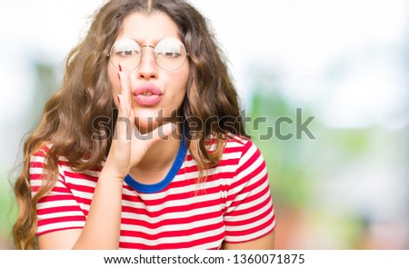 Young beautiful woman wearing glasses hand on mouth telling secret rumor, whispering malicious talk conversation