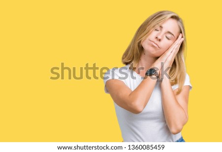 Beautiful young woman wearing casual white t-shirt over isolated background sleeping tired dreaming and posing with hands together while smiling with closed eyes.