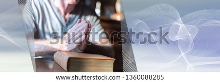 Man sitting at a table praying hands on a bible. panoramic banner