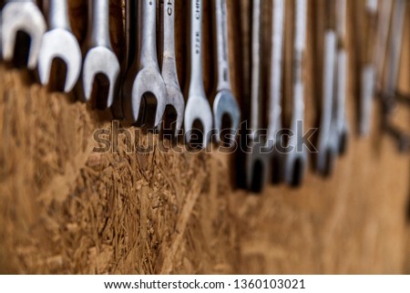 Wrenches sorted by size on a wood wall isolated