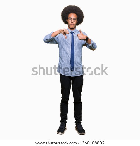Young african american business man with afro hair wearing glasses Doing thumbs up and down, disagreement and agreement expression. Crazy conflict