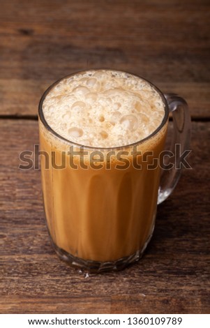 Tea with milk popularity known as "Teh Tarik" is a drink popular in Malaysia place on the wooden table.