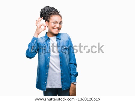Young braided hair african american girl wearing glasses over isolated background smiling positive doing ok sign with hand and fingers. Successful expression.