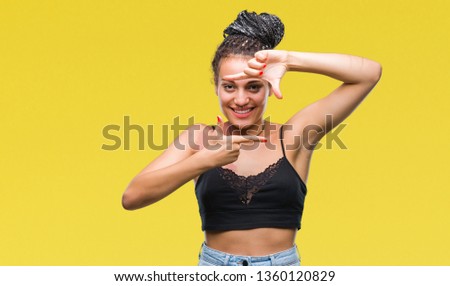 Young braided hair african american with pigmentation blemish birth mark over isolated background smiling making frame with hands and fingers with happy face. Creativity and photography concept.