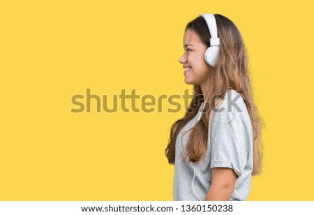 Young beautiful woman wearing headphones listening to music over isolated background looking to side, relax profile pose with natural face with confident smile.