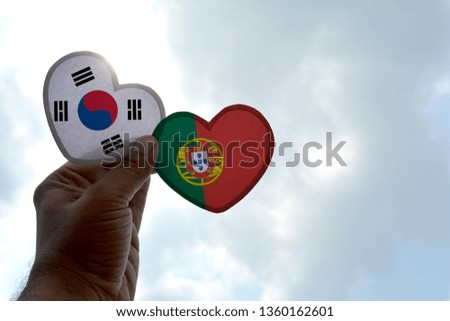 Hand holds a heart Shape South Korea and Portugal flag, love between two countries