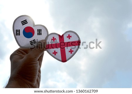 Hand holds a heart Shape South Korea and Georgia flag, love between two countries