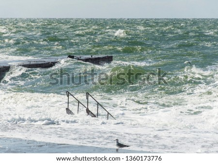 Beautiful picture of the Black Sea coast. Sea water, waves, a small storm and a sunny day. The ladder descends directly into the sea.