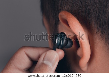 close up of adult caucasian male with earphones in the ear Royalty-Free Stock Photo #1360174250