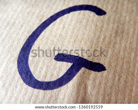 the alphabetical capital block letter G writed on wrapping paper using a black felt tip pen