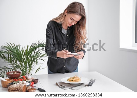 Female food photographer with mobile phone taking picture of tasty food at home