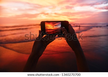 Girl takes a sunset photo on the phone.