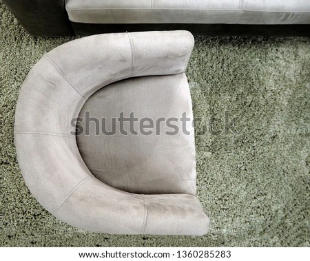 Top view of a semicircular gray armchair on a green  gray  carpet.  Royalty-Free Stock Photo #1360285283