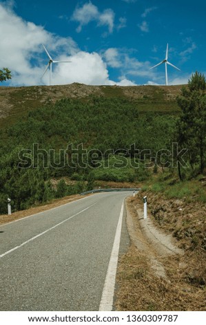 Countryside road passing through hilly landscape with several wind turbines, in a sunny day at Serra da Estrela. The highest mountain range in continental Portugal, with astonishing scenery.