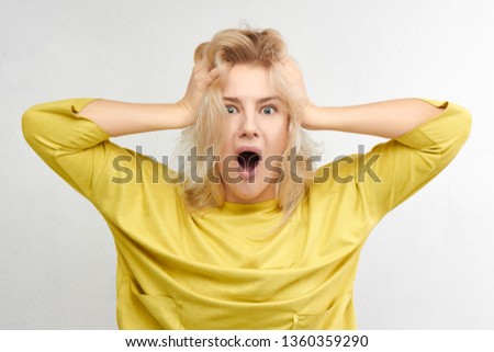 Woman in horror holds head with hands and screams of fear, anger and surprise isolated on white background. Something terrible and unexpected happened, expressive emotions