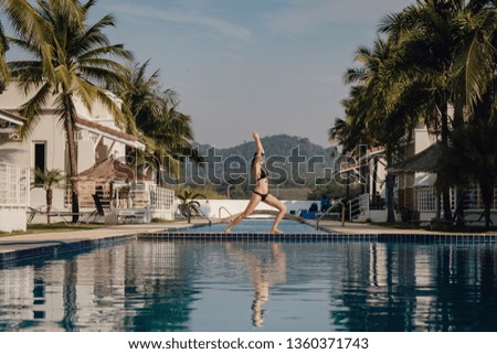 young woman practicing pose yoga on swimming pool and the nature beach at sunset or sunrise. Yoga and Healthy Concept. Warrior I or Virabhadrasana Pose