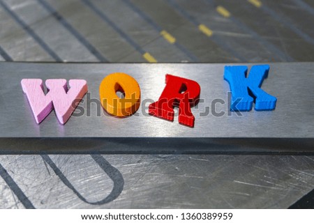 Multi-colored letters of the word work on a metal plate on the production