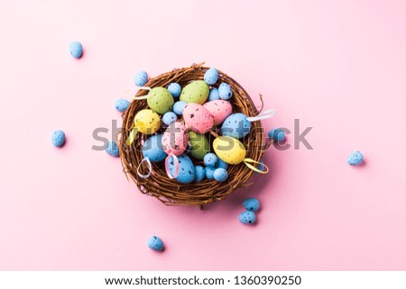 Colorful decor easter eggs in a nest on pastel pink background. Flat lay
