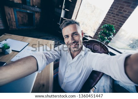 Close up photo handsome he him his macho guy cheer friendly look watch telephone smart phone make take selfies toothy smile notebook table stand office wear specs formal wear white shirt