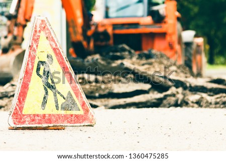 Road works warning sign with weathered and damaged surface,  symbol.