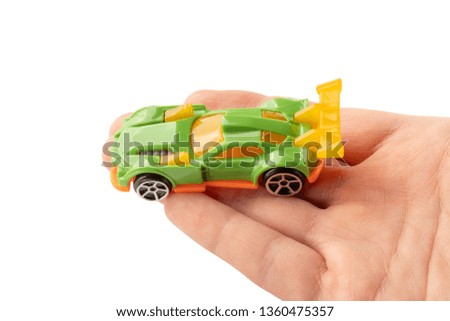 Yellow and green car toy in hand on the palm