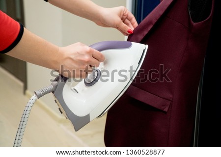 Woman Ironing Clothes With Steam Iron At Home