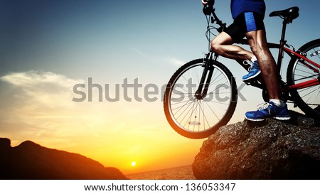 Young athlete standing on a rock with bicycle