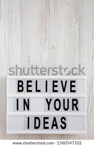 'Believe in your ideas' words on modern board over white wooden background. Flat lay, from above, overhead. Copy space.