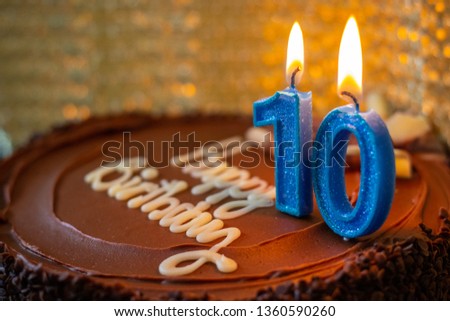 Happy 10 birthday celebration . Chocolate cake and blue candles. Image not in focus.