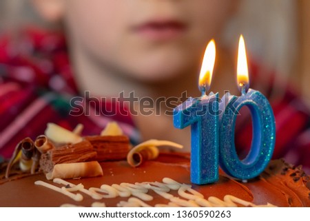 Happy 10 birthday celebration . Chocolate cake and blue candles. Image not in focus.