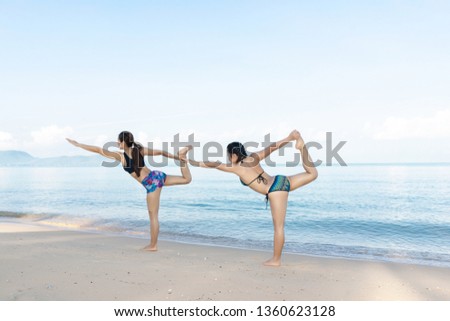 Healthy women are exercising with yoga on the beach in the blue sky.
